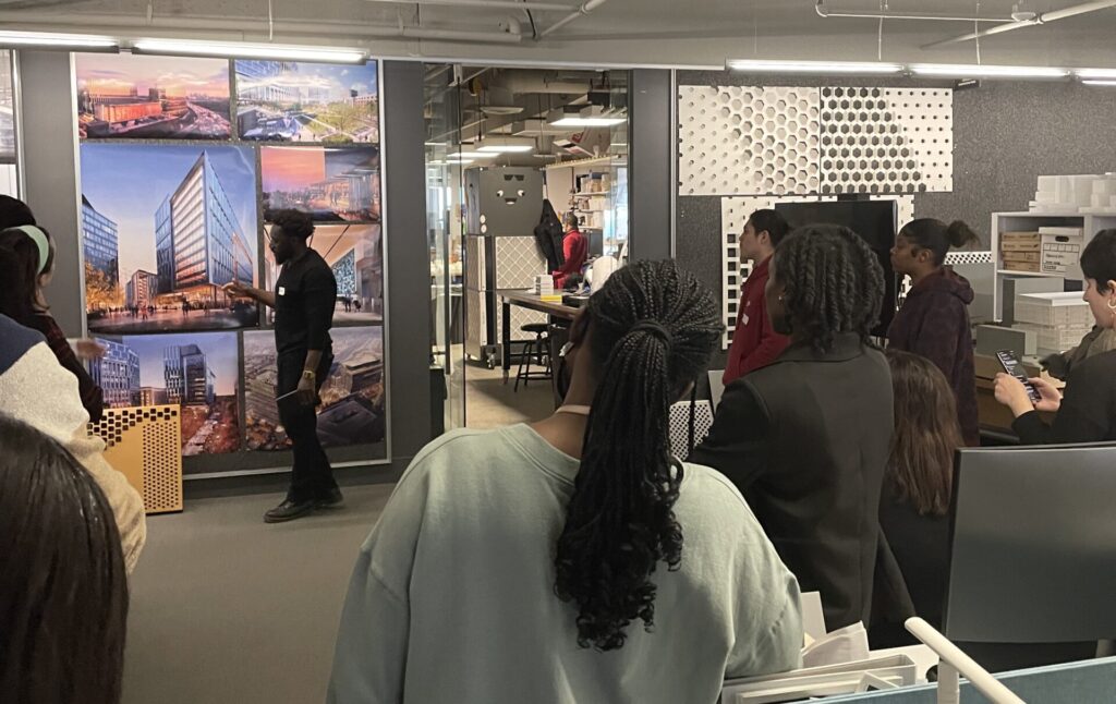 An image of the program touring the Boston office of the design firm, Perkins&Will.  One of the staff designers is presenting images of a recently-begun tower project in downtown Boston.  